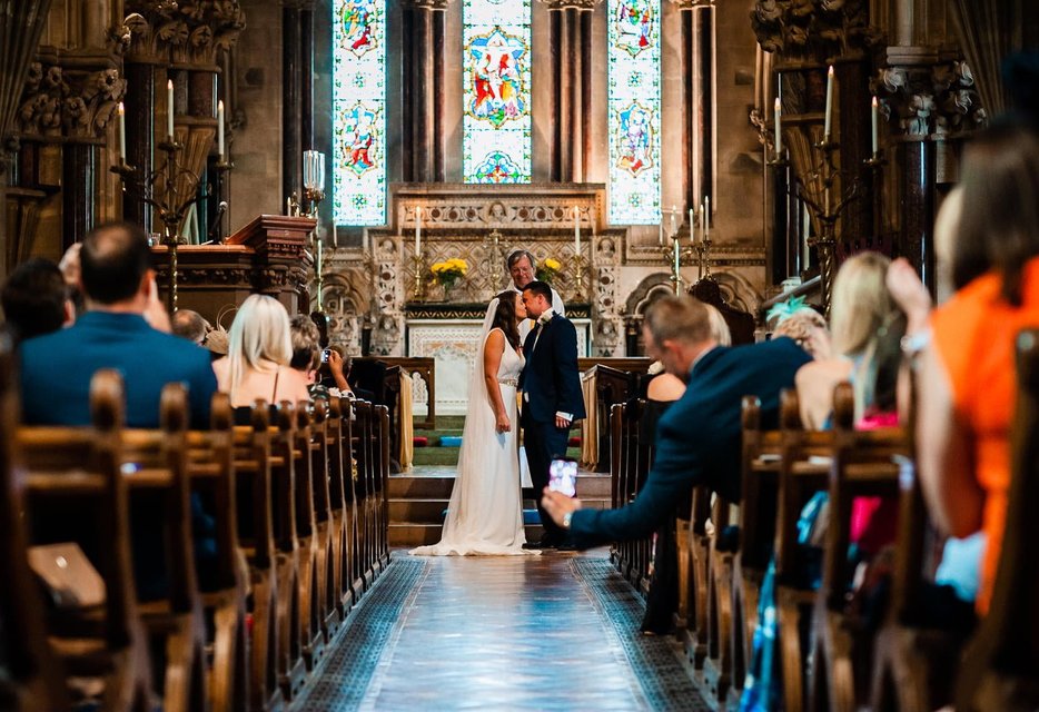 Bride and groom walking down aisle with guests watching without phones