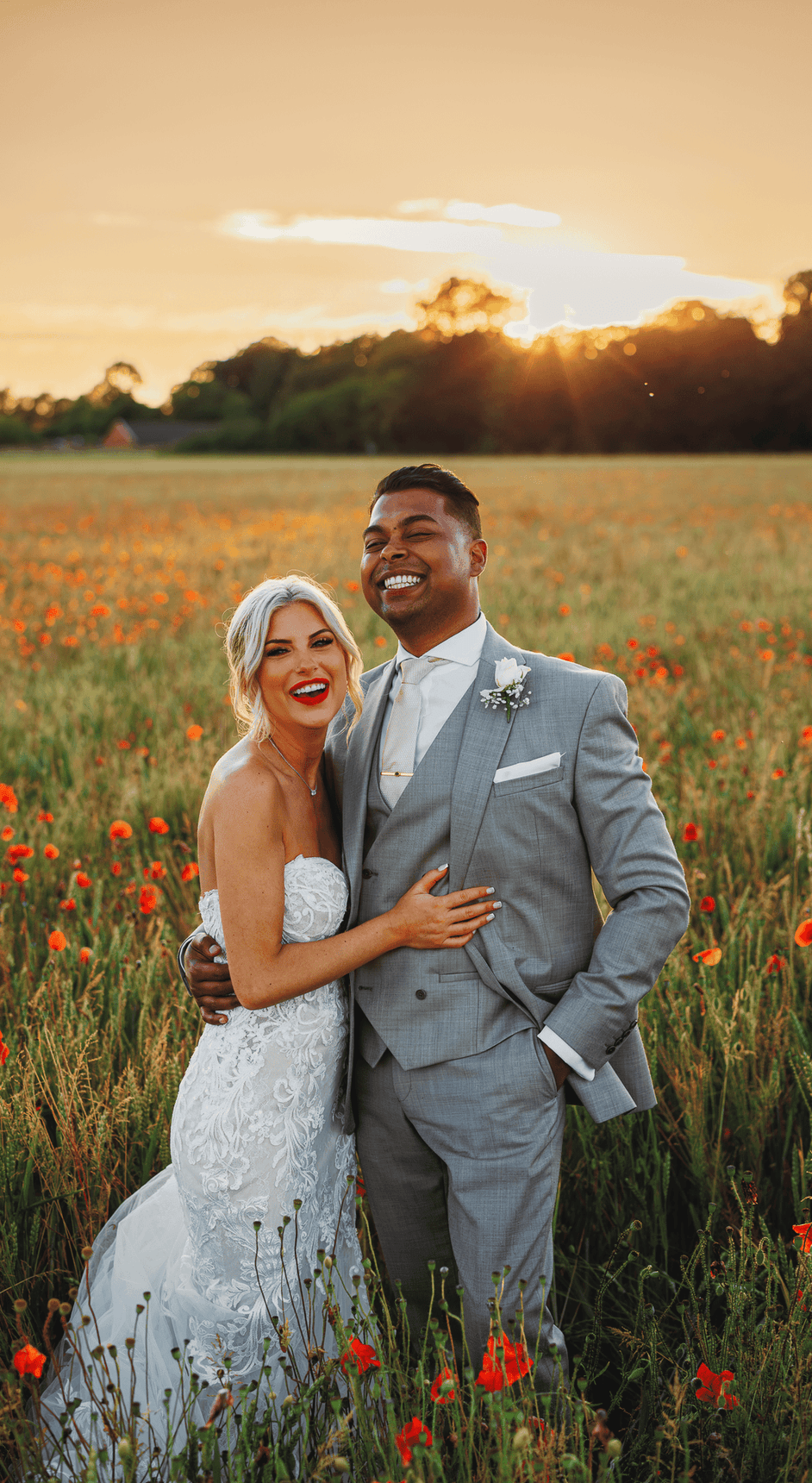 Groom and bride posing in field of flowers at sunset