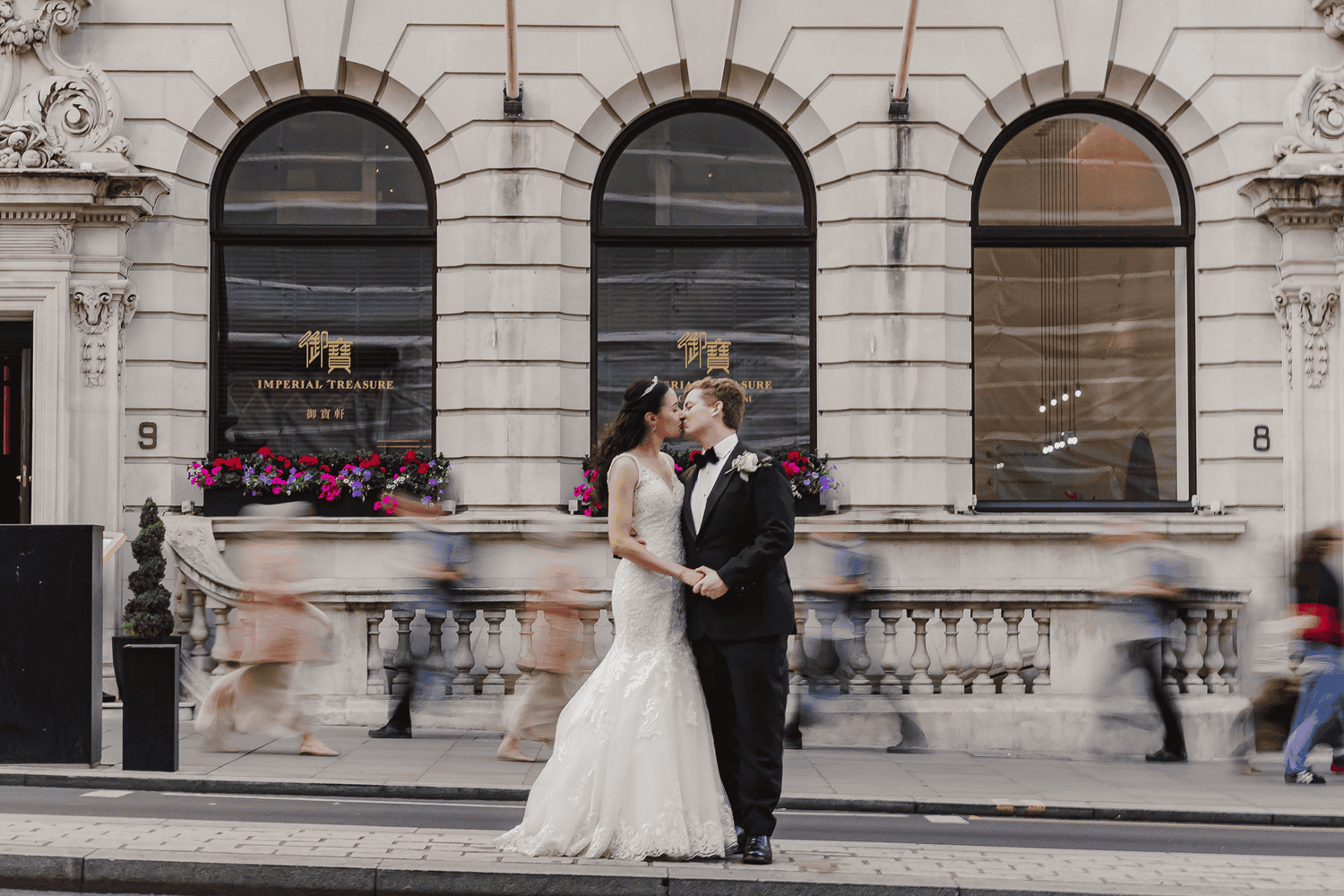 Bride and groom standing in the street with London traffic passing by