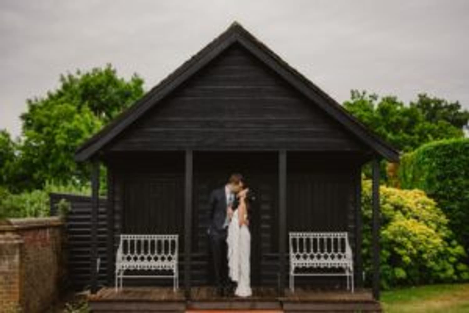 Bride and groom kissing in romantic garden outhouse