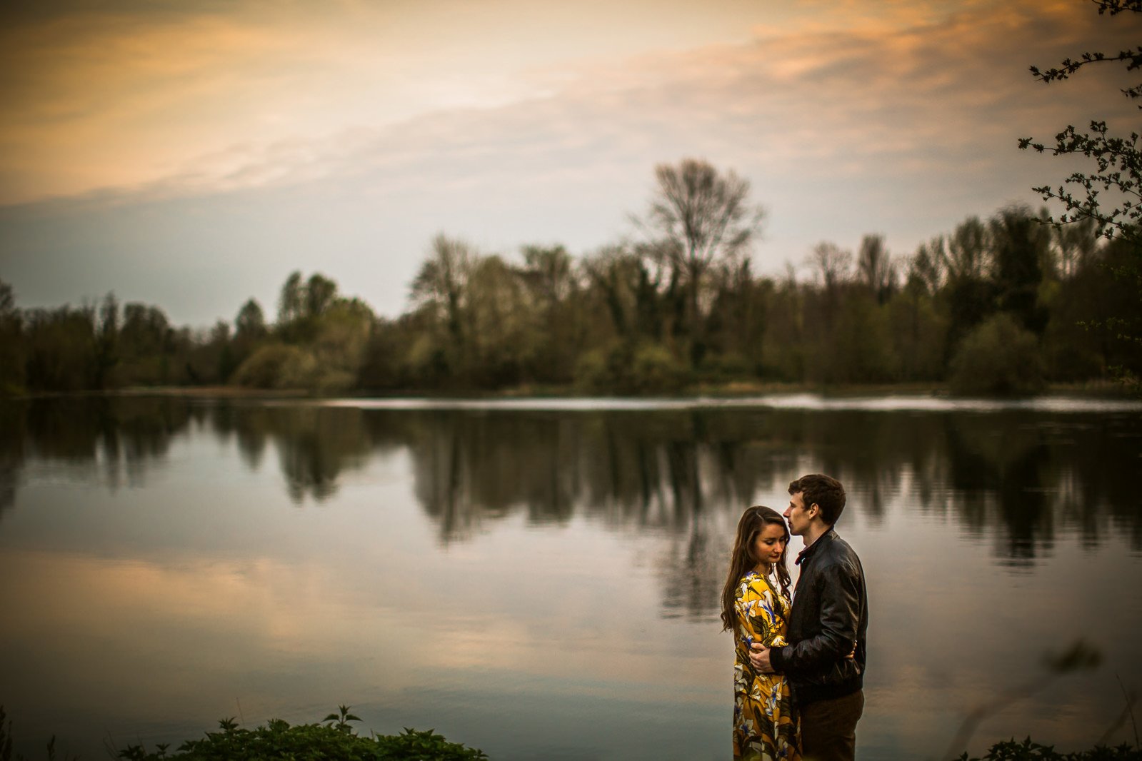 Couple in coordinated navy and cream outfits embracing during engagement shoot